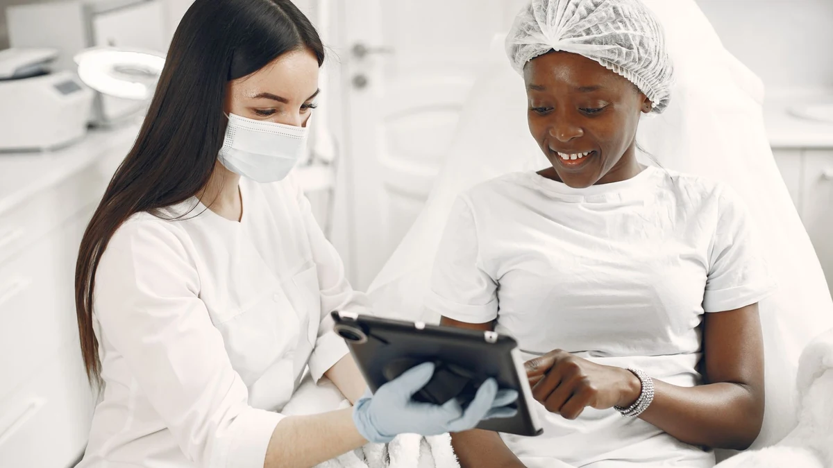 Dermatologist reviewing personalized laser hair reduction parameters on digital tablet with patient