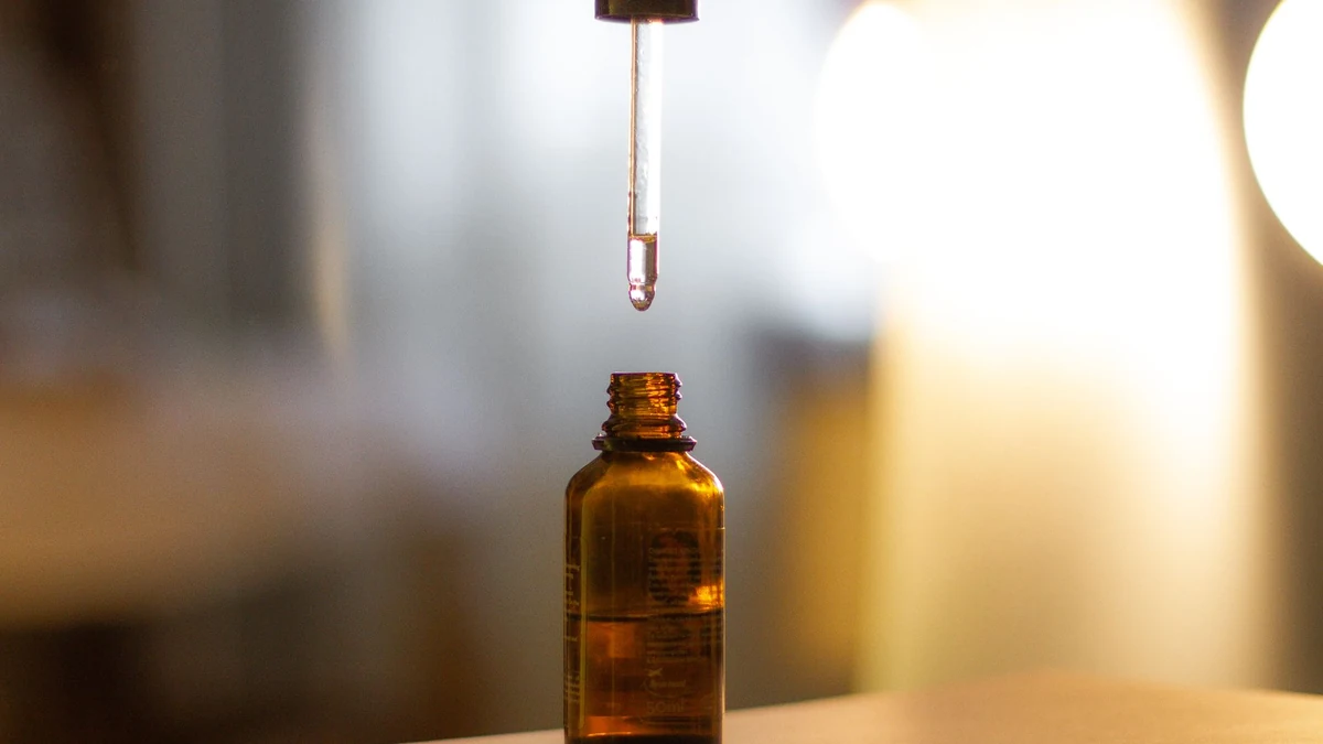 Close-up of amber glass bottle and precision glass dropper dispensing concentrated antioxidant serum