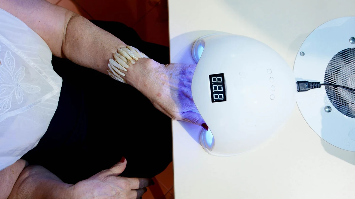 Client curing structured hard gel nail extensions inside UV LED lamp