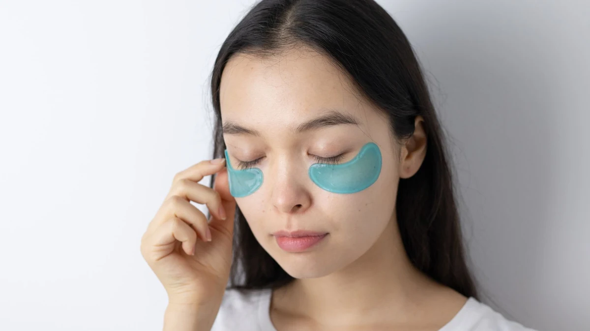 Young woman applying calming hydrogel cooling patches under both eyes for skin puffiness relief