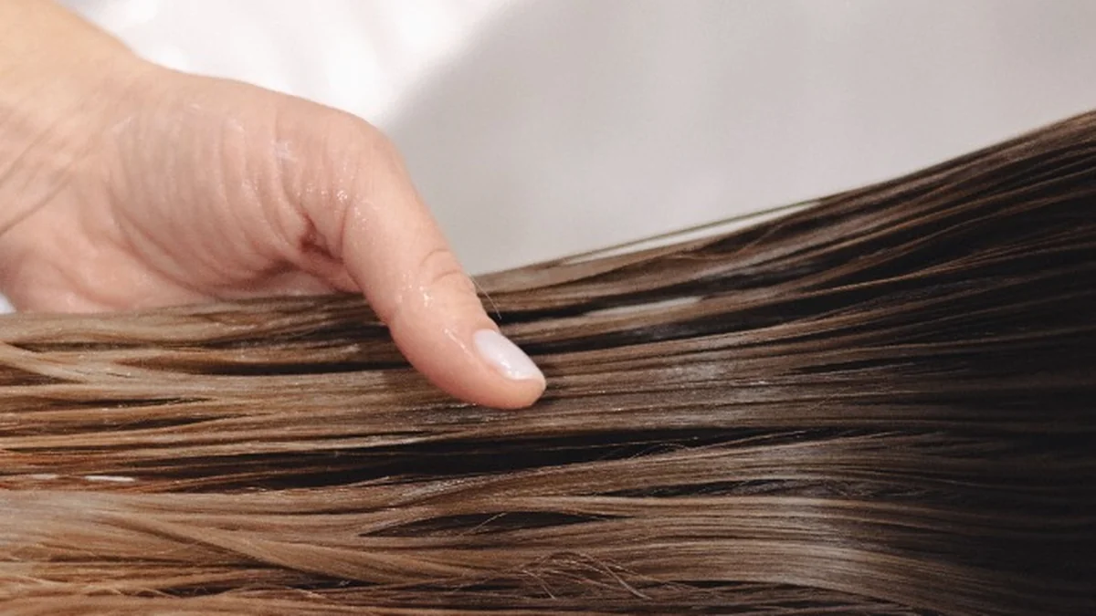 Salon stylist washing and clarifying hair at wash basin before keratin application