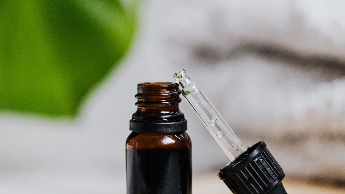 Amber dropper bottle with nourishing botanical hair oil and dropper on wooden vanity