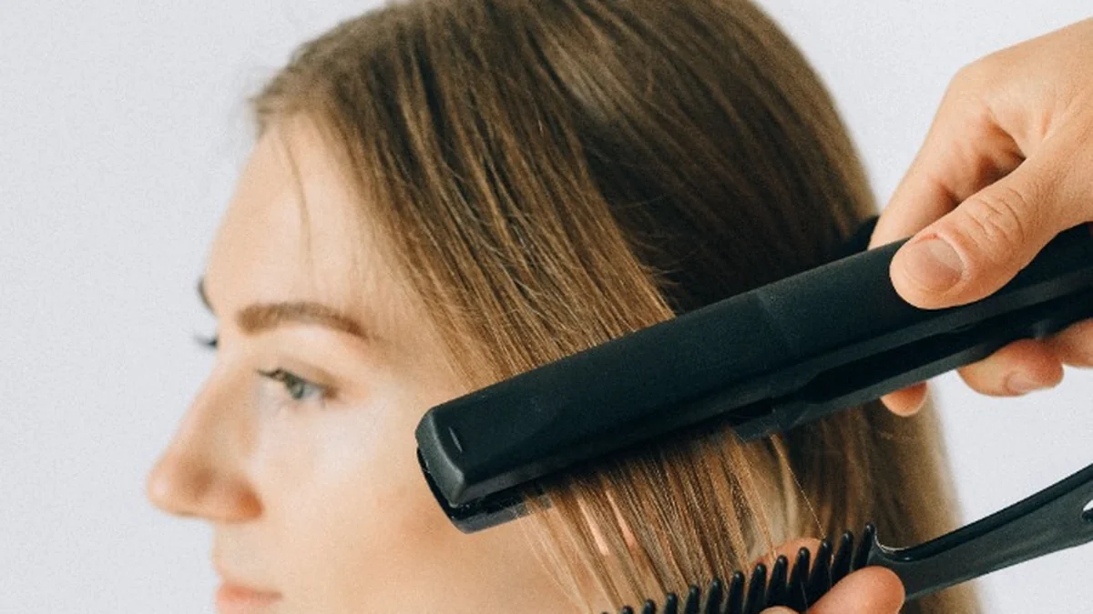 Stylist using professional flat iron to seal keratin smoothing formula into hair