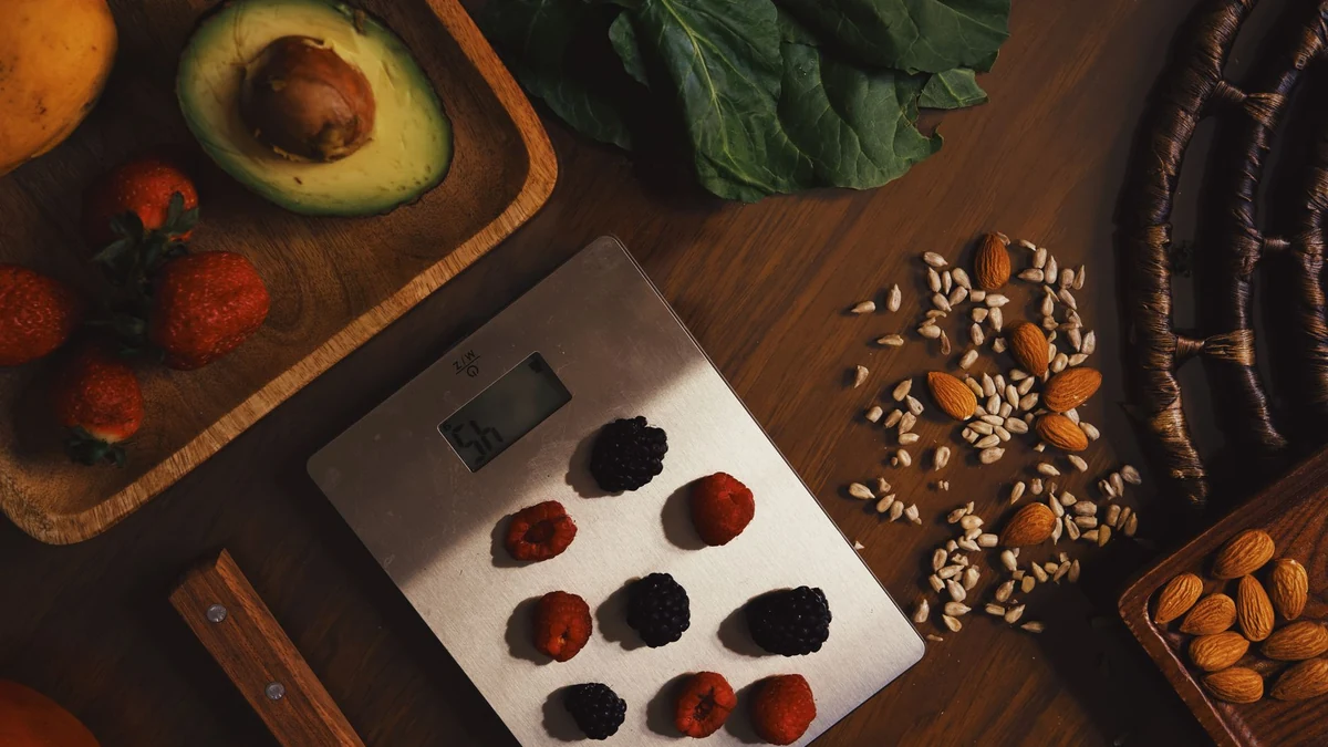 Fresh avocado, raw almonds, sunflower seeds and nutrient-rich berries on kitchen scale